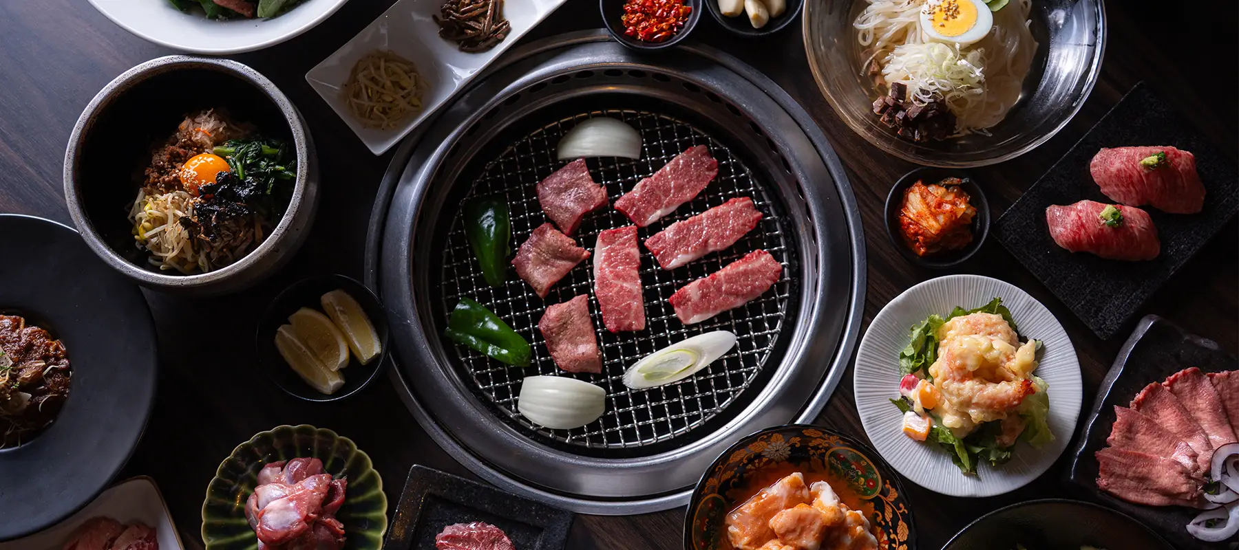 焼き網を囲むように焼肉やビビンバ、冷麺が並ぶテーブル